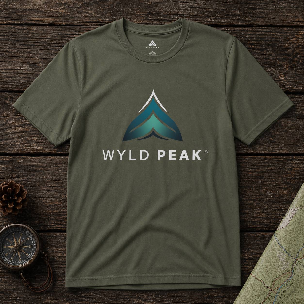 Green t-shirt with Wyld Peak logo on a wooden surface