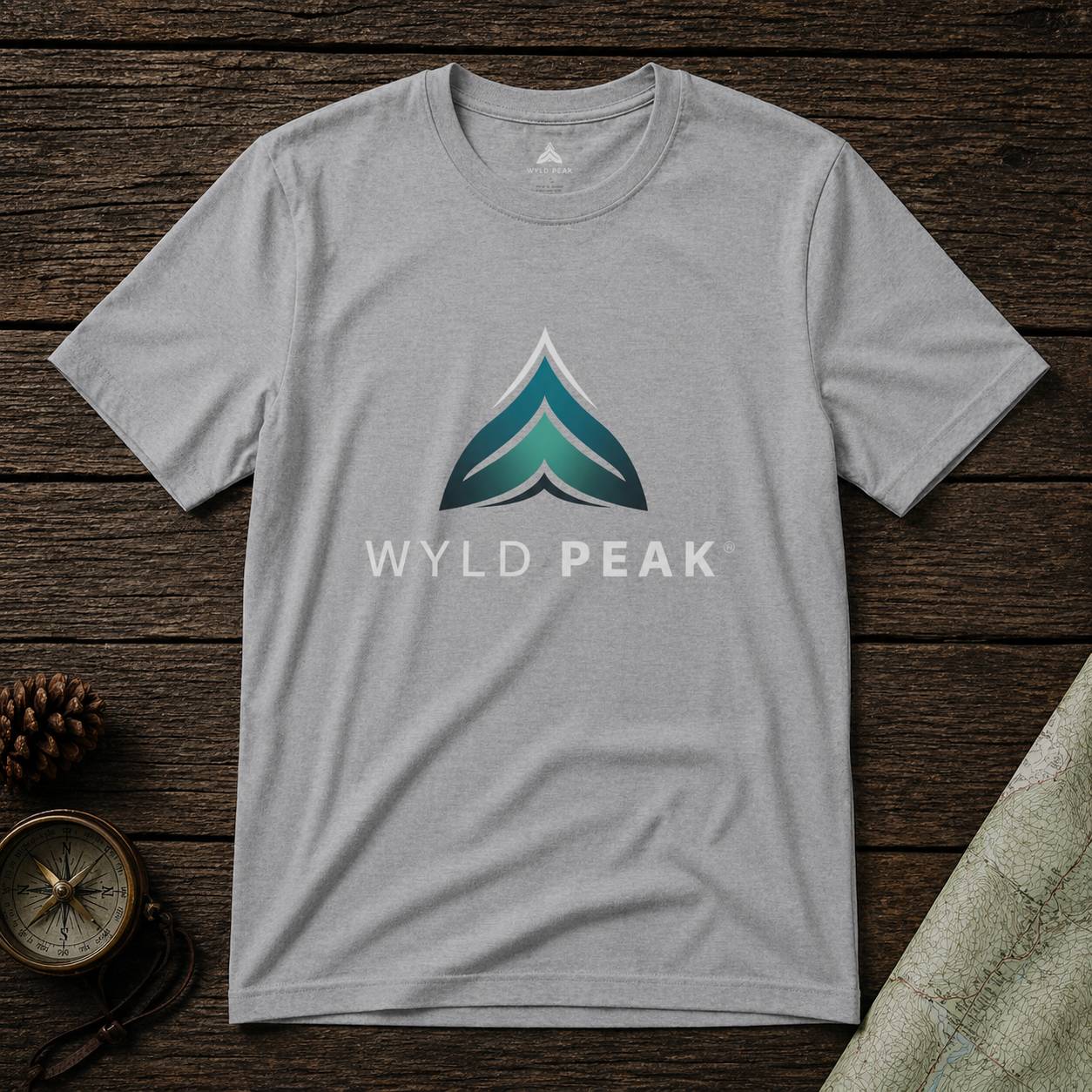 Gray t-shirt with Wyld Peak logo on a wooden surface