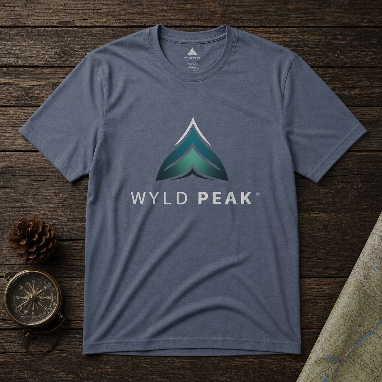 Blue t-shirt with Wyld Peak logo on a wooden surface