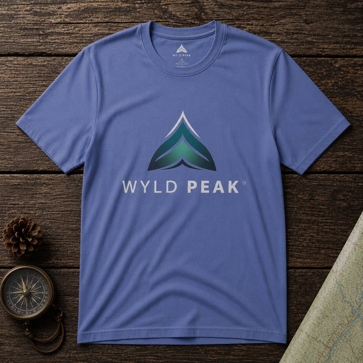 Blue t-shirt with Wyld Peak logo on a wooden surface