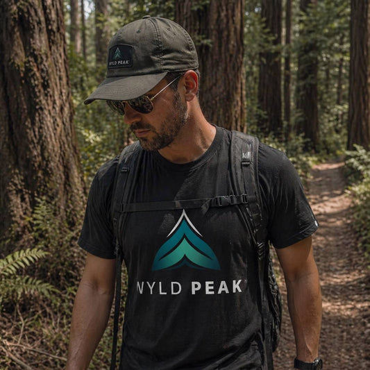 Man wearing a black t-shirt with 'Wyld Peak' logo in a forest setting
