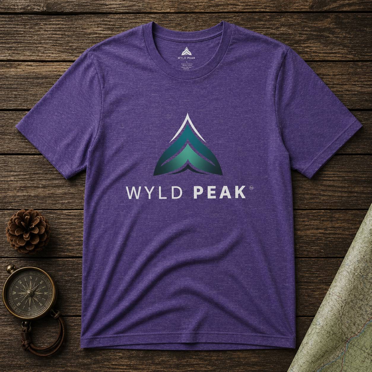 Purple t-shirt with Wyld Peak logo on a wooden surface