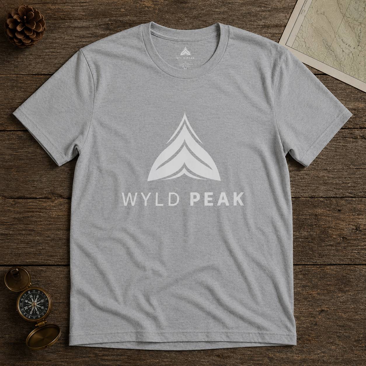 Gray t-shirt with 'Wyld Peak' logo on a wooden surface
