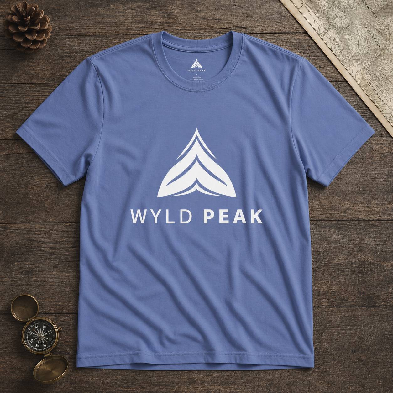 Blue t-shirt with 'Wyld Peak' logo on a wooden surface