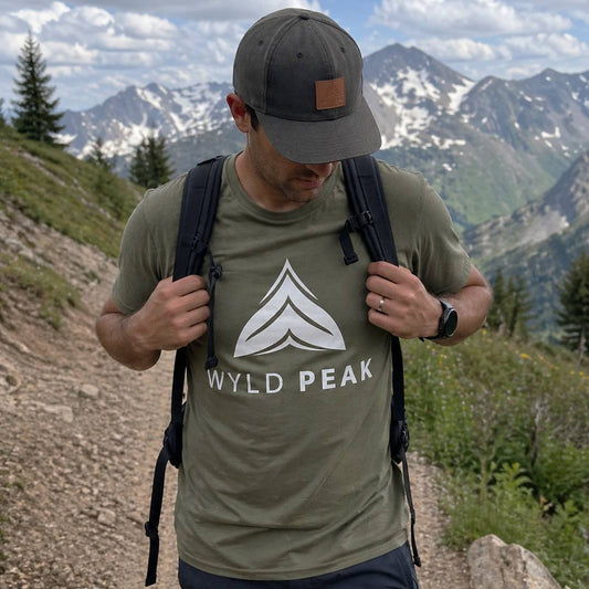 Man hiking with a Wyld Peak t-shirt and backpack in a mountainous area