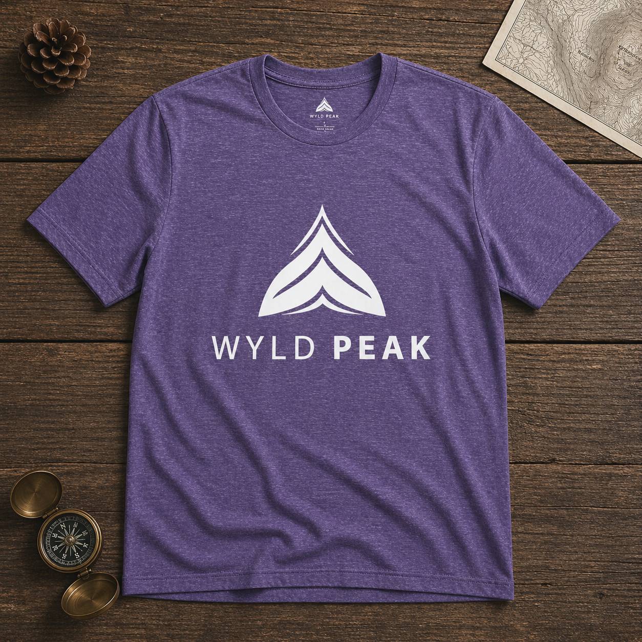 Purple t-shirt with 'Wyld Peak' logo on a wooden surface