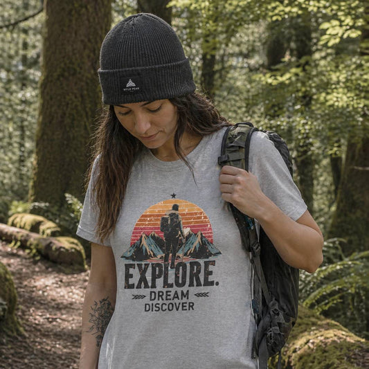 Person wearing a t-shirt with 'Explore. Dream Discover' in a forest setting