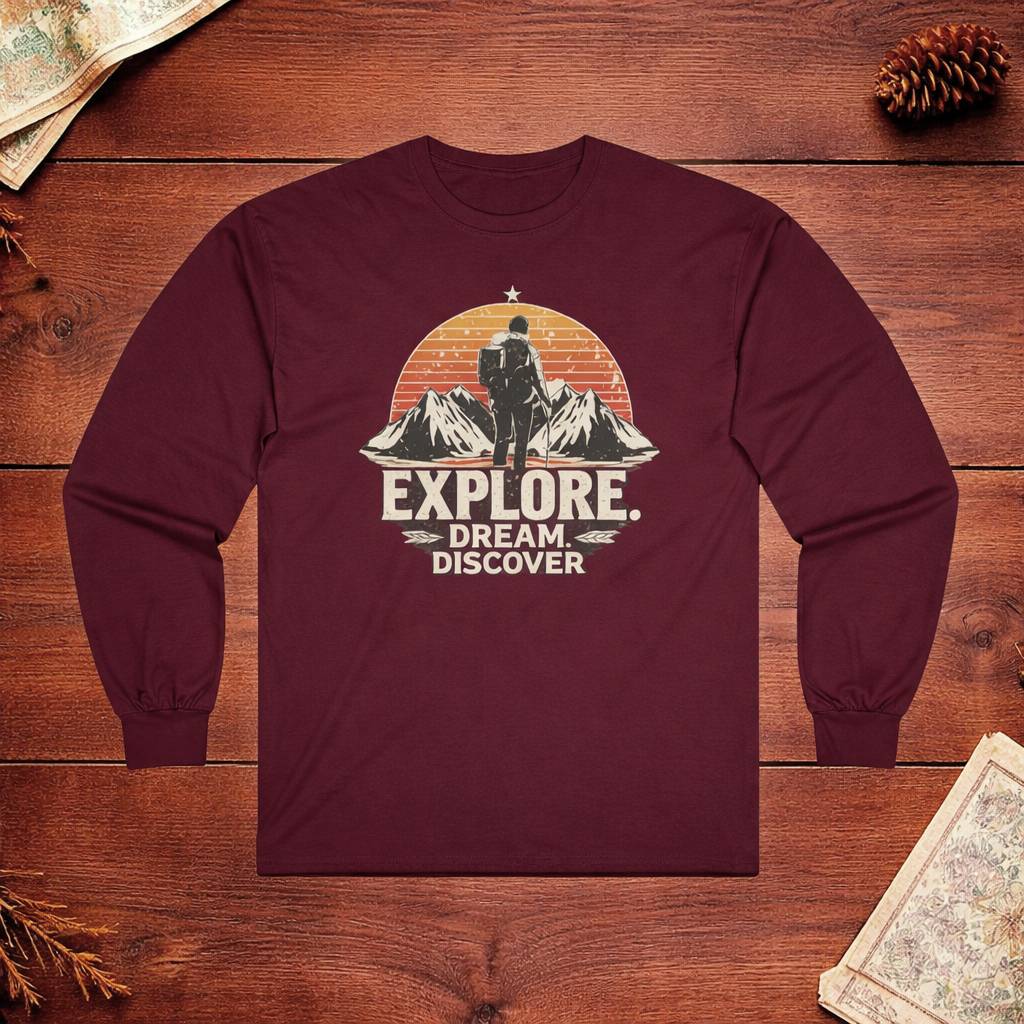 Maroon long-sleeve shirt with 'Explore. Dream. Discover.' graphic on a wooden surface.