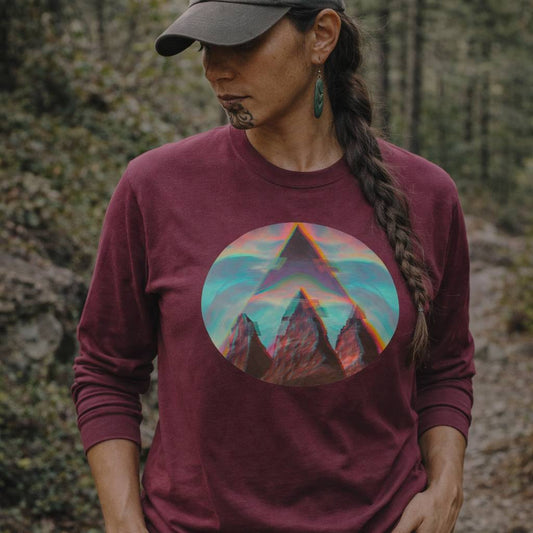 Person wearing a maroon long-sleeve shirt with a mountain graphic in a forest setting