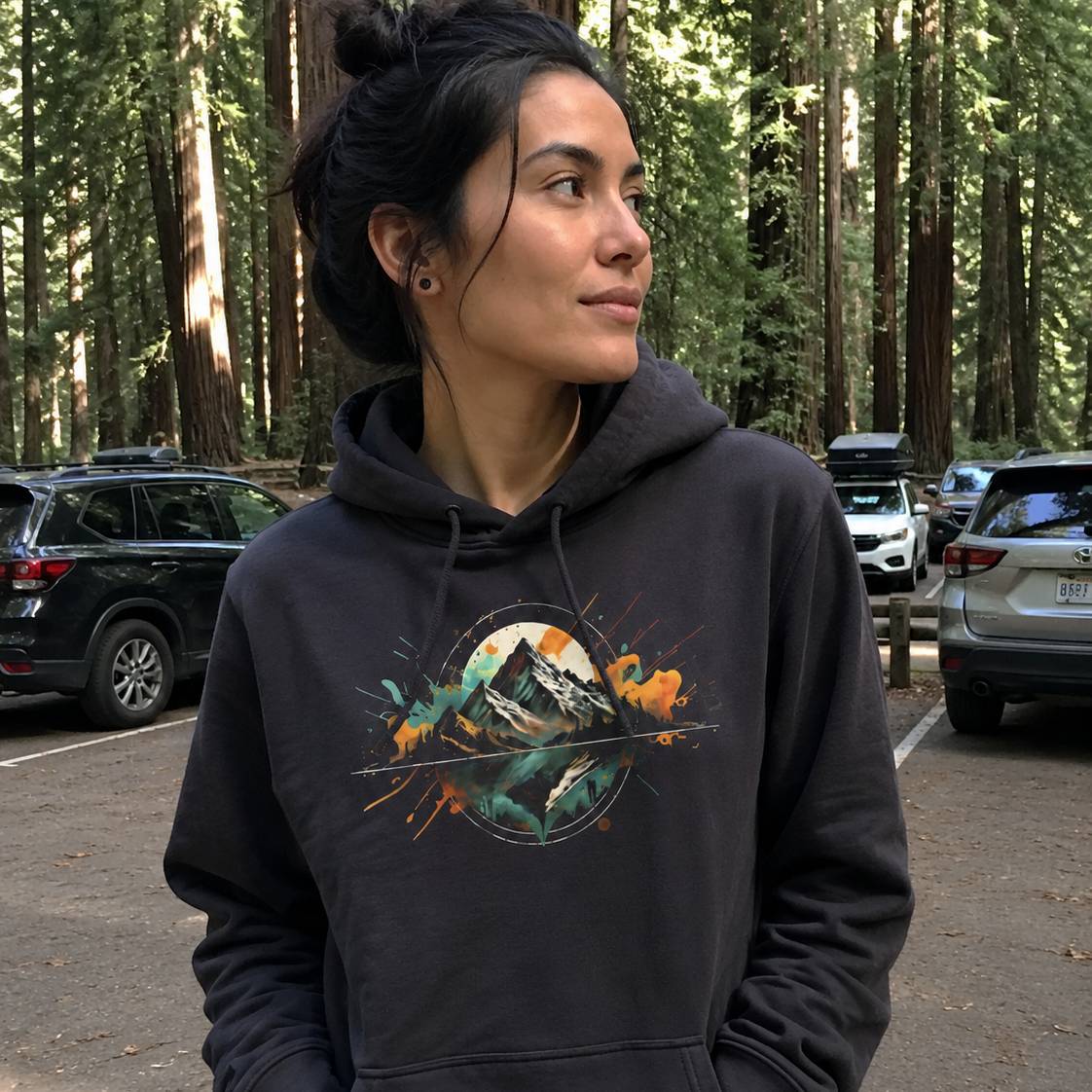 Woman wearing a hoodie with a nature graphic in a forest setting