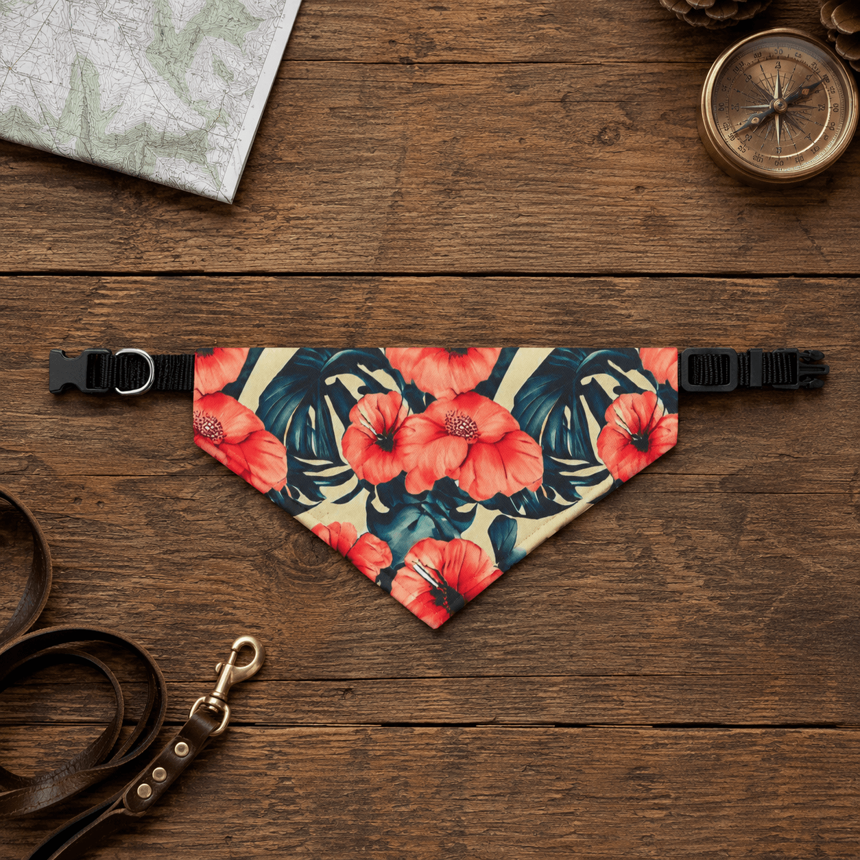 Floral patterned dog bandana on a wooden surface with a leash and compass.