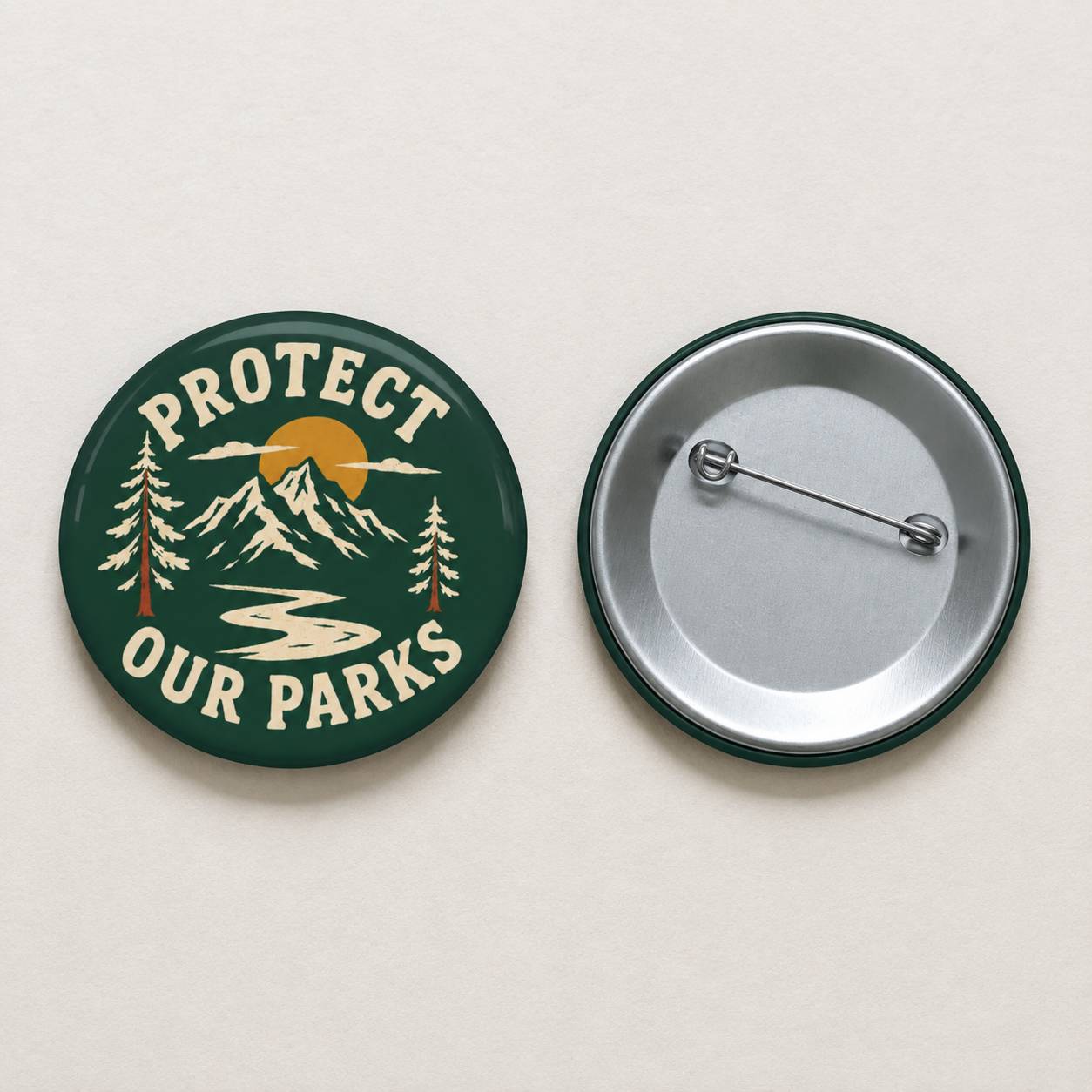 Two round pinback buttons on a light beige background. The left button is front-facing and dark green with cream text reading 'PROTECT OUR PARKS,' plus a mountain, trees, and sun graphic.