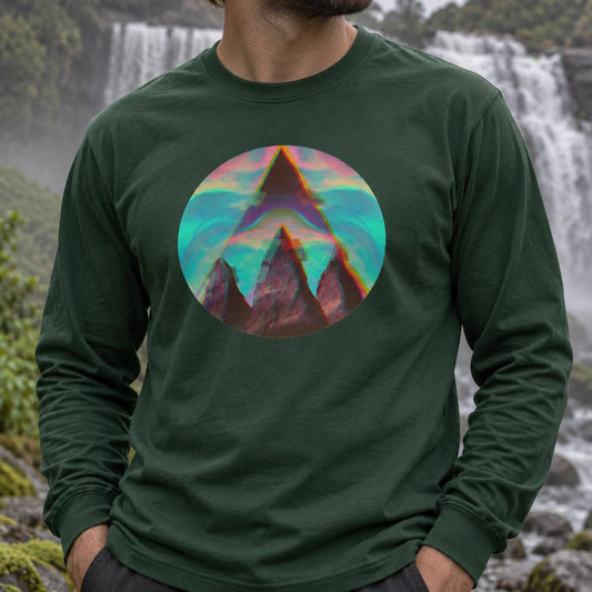A man wearing a dark forest green long-sleeve t-shirt with a colorful circular graphic of a mountain peak on the chest, set against a blurred background of waterfalls and greenery.