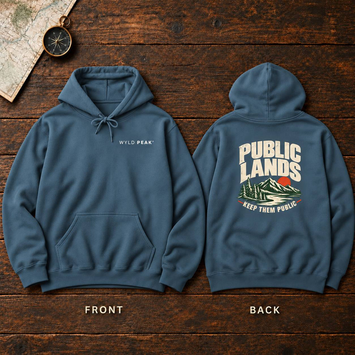 A slate blue hoodie shown from both front and back on a dark wood background. The front has a small white 'WYLD PEAK' logo on the left chest, and the back features a large cream, green, and red graphic reading 'PUBLIC LANDS KEEP THEM PUBLIC' with mountains.