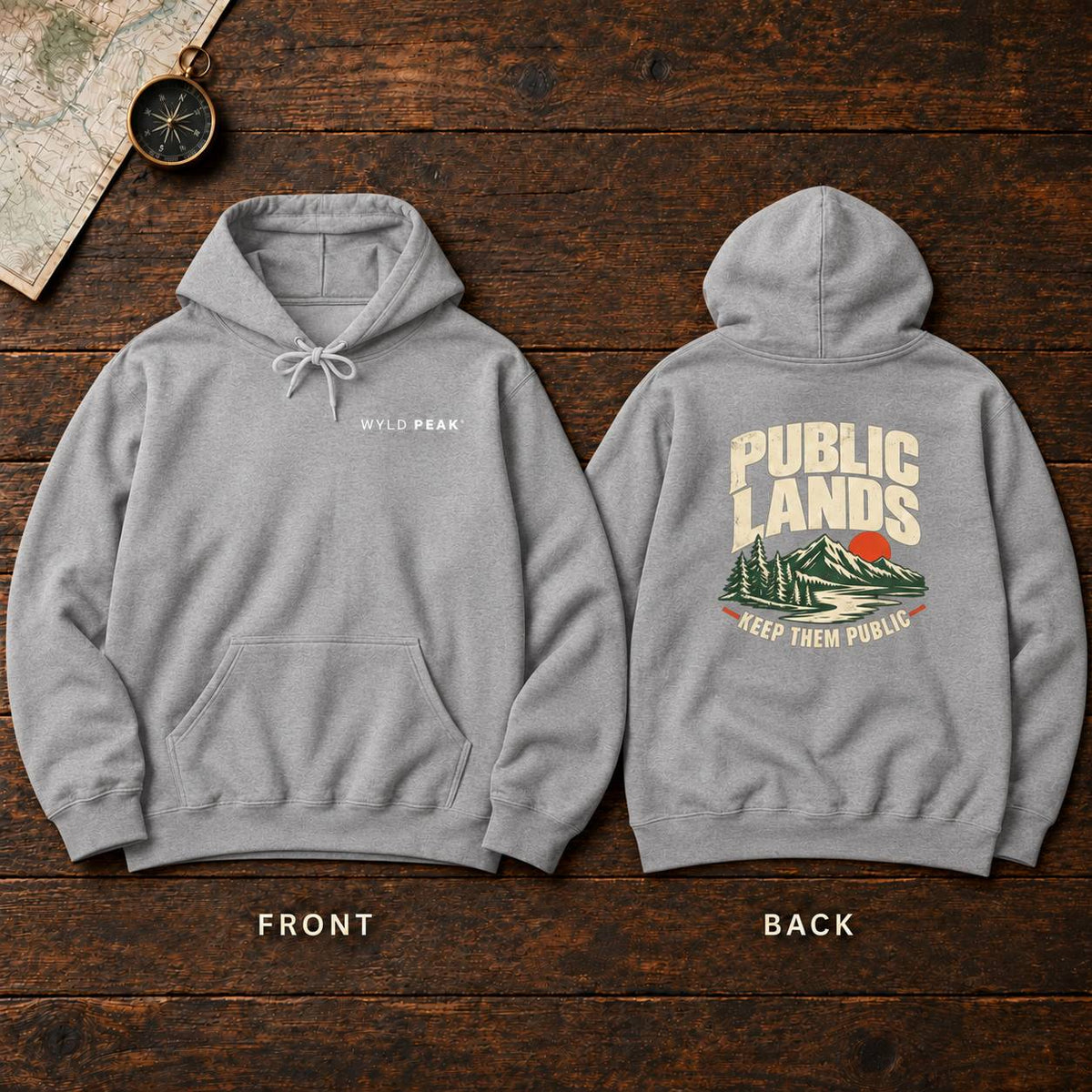 A light gray pullover hoodie shown from both front and back on a dark wood background. The front has a small white 'WYLD PEAK' text on the left chest, and the back has a large graphic with the words 'PUBLIC LANDS' above a mountain illustration and 'KEEP THEM PUBLIC' below.