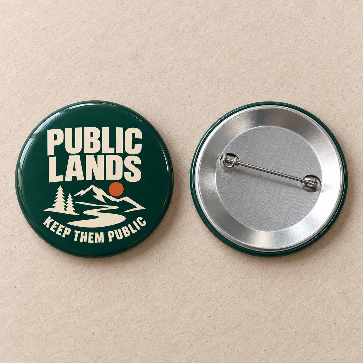 Two round pinback buttons on a beige textured background. The left button is dark green with white text reading 'PUBLIC LANDS' and 'KEEP THEM PUBLIC' above a white mountain, tree, and river graphic with a small orange sun.