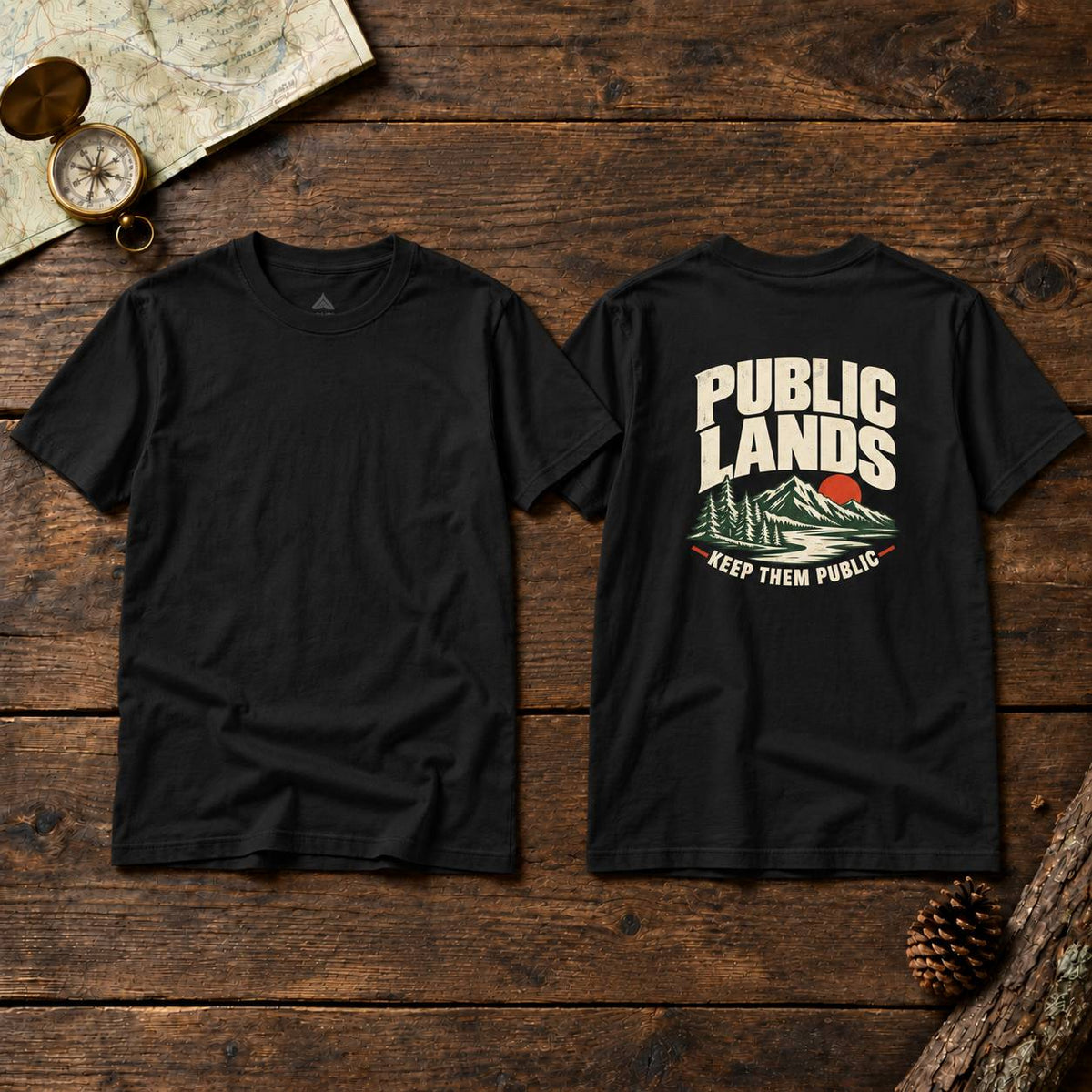 Two black short-sleeve T-shirts displayed flat on a rustic wooden surface, showing both the front and back views. The front is plain black, while the back features a large graphic print with the words 'PUBLIC LANDS' in cream, a red sun, green mountains, and the phrase 'KEEP THEM PUBLIC' in red.