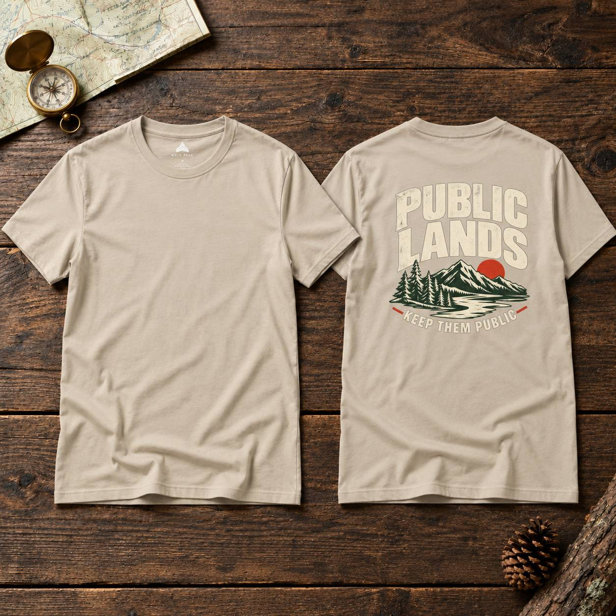 Two beige crewneck t-shirts displayed side-by-side on a dark wood background, showing both the front and back views. The front is plain, while the back features a graphic print with the text 'PUBLIC LANDS' in a distressed cream font above an illustration of pine trees, mountains, and a red sun, with 'KEEP THEM PUBLIC' written below.