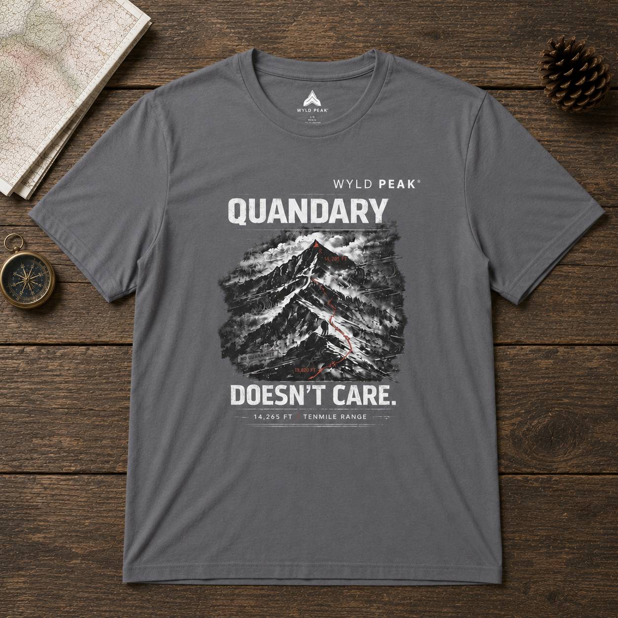Gray t-shirt with mountain graphic and text on a wooden surface