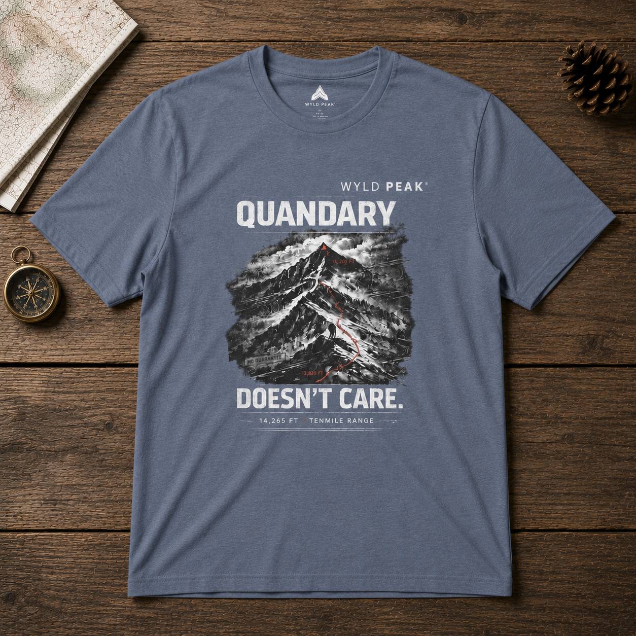 Blue t-shirt with mountain graphic and text on a wooden surface