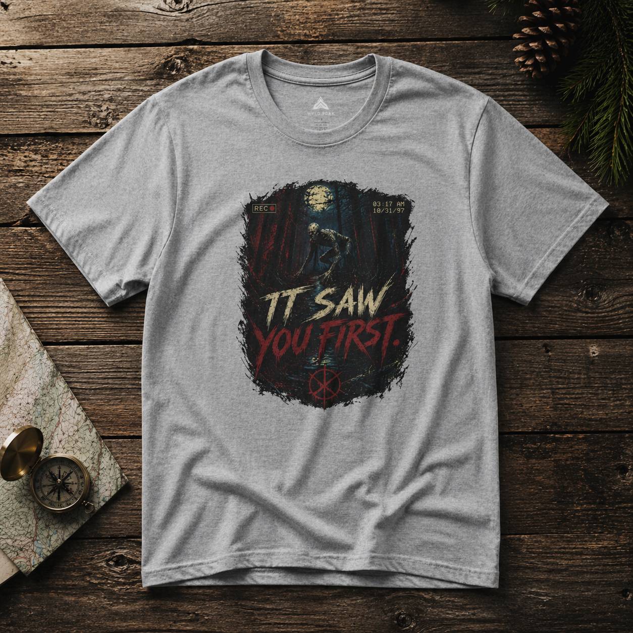 Gray t-shirt with rake graphic design and text on a wooden surface