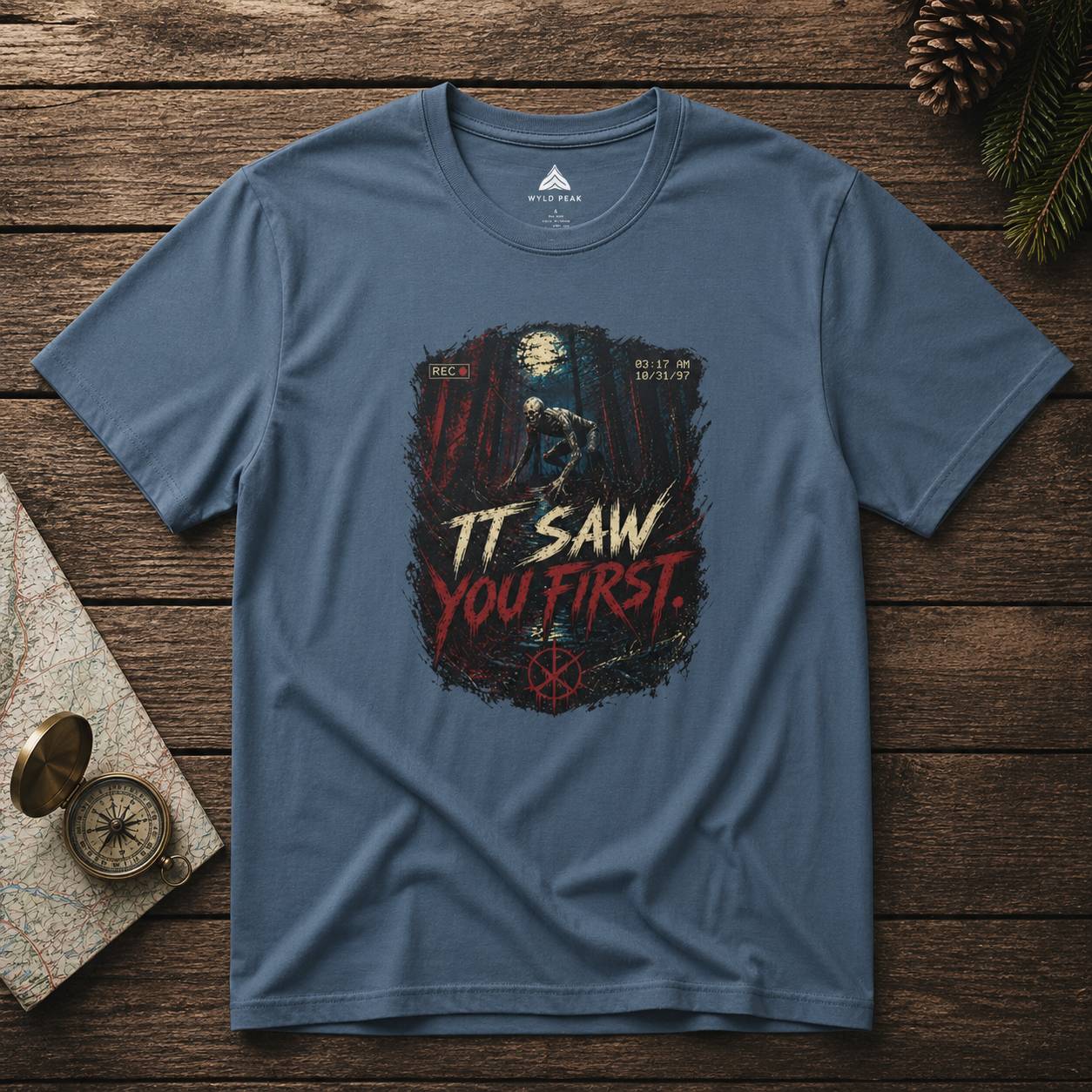 Blue t-shirt with rake graphic design on a wooden surface