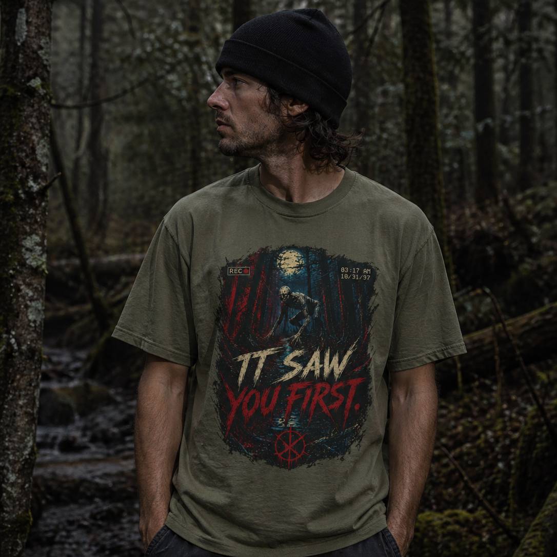 Man wearing a t-shirt with a graphic rake design in a forest setting