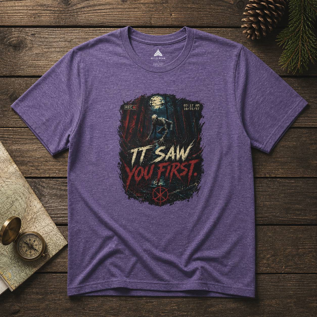 Purple t-shirt with rake graphic design and text on a wooden surface