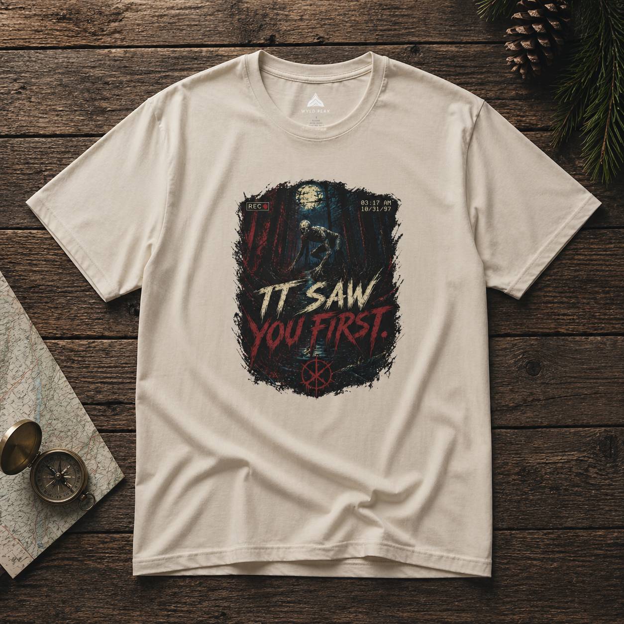 Beige t-shirt with rake graphic design and text on a wooden surface
