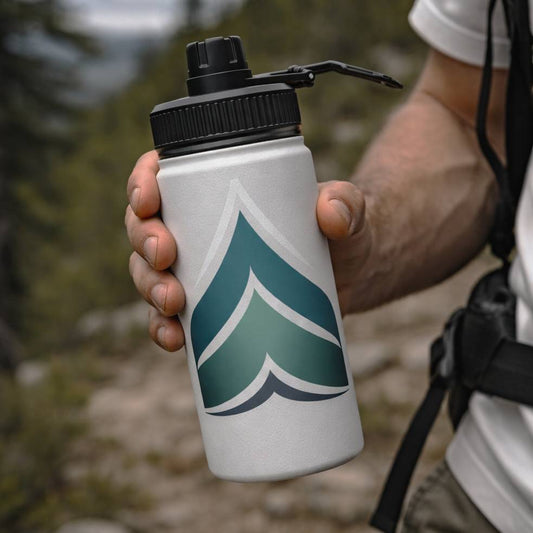 Person holding a water bottle with a Wyld Peak logo in a natural setting