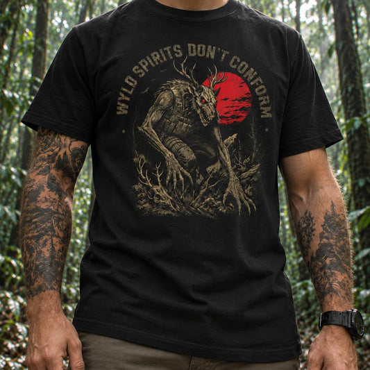 A man wearing a black graphic t-shirt with a distressed design of a horned creature and a red sun, with the text 'WYLD SPIRITS DON'T CONFORM'. The background is a blurred forest.