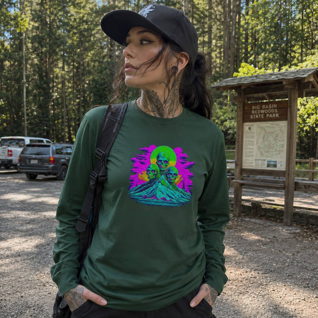 Woman wearing a green long-sleeve shirt with a colorful graphic design in a forest setting.