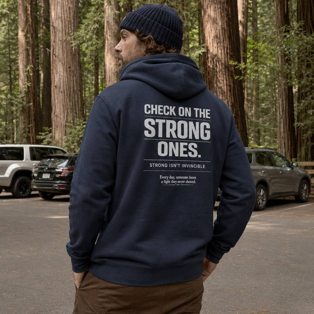 Person wearing a navy hoodie with motivational text in a forest setting