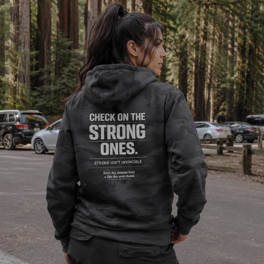 Person wearing a black hoodie with motivational text in a forest setting