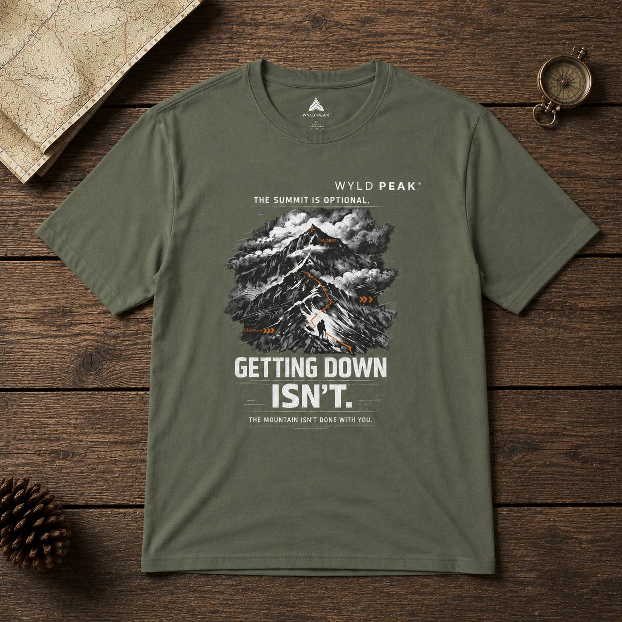 Green t-shirt with mountain graphic and text on a wooden surface