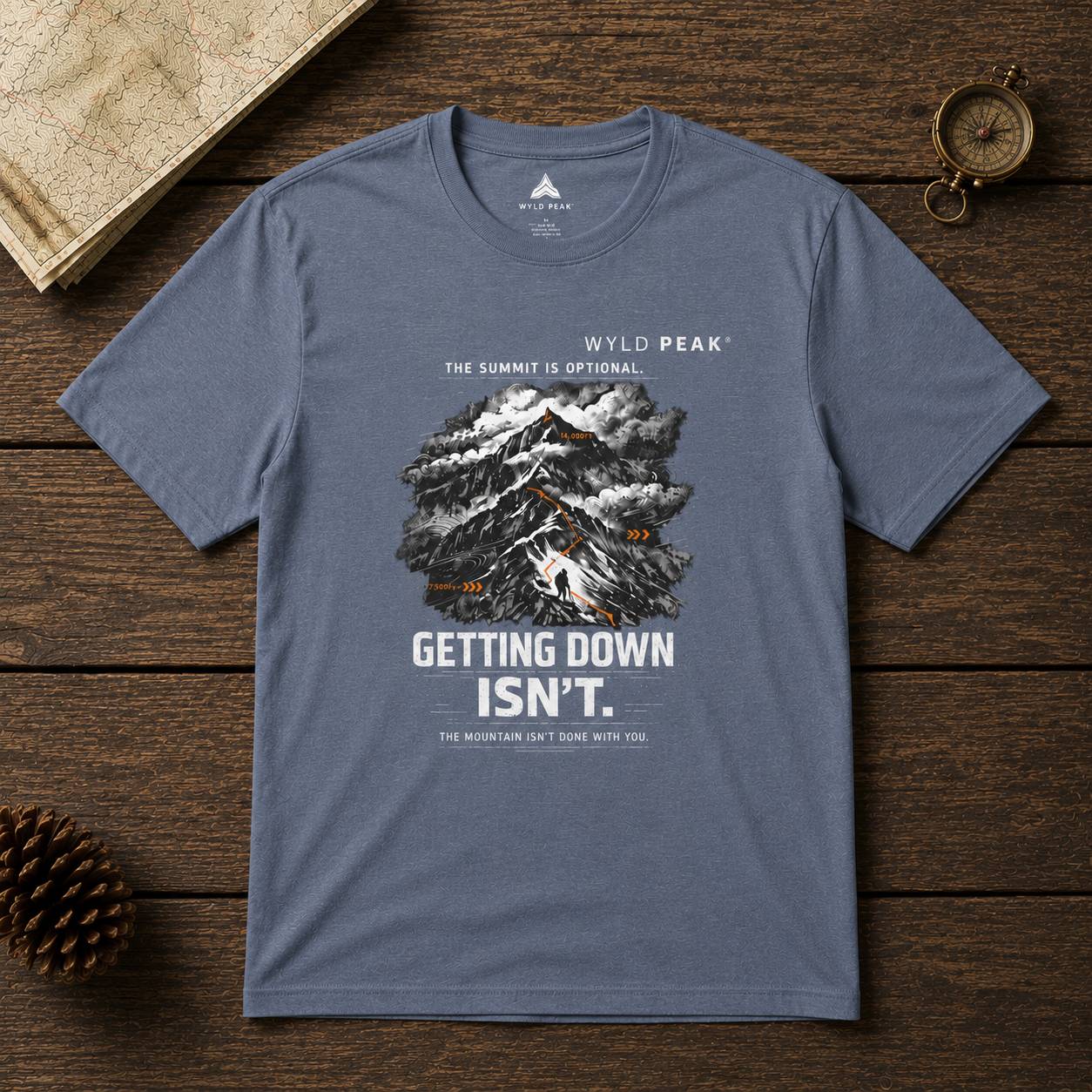 Blue t-shirt with mountain graphic and text on a wooden surface