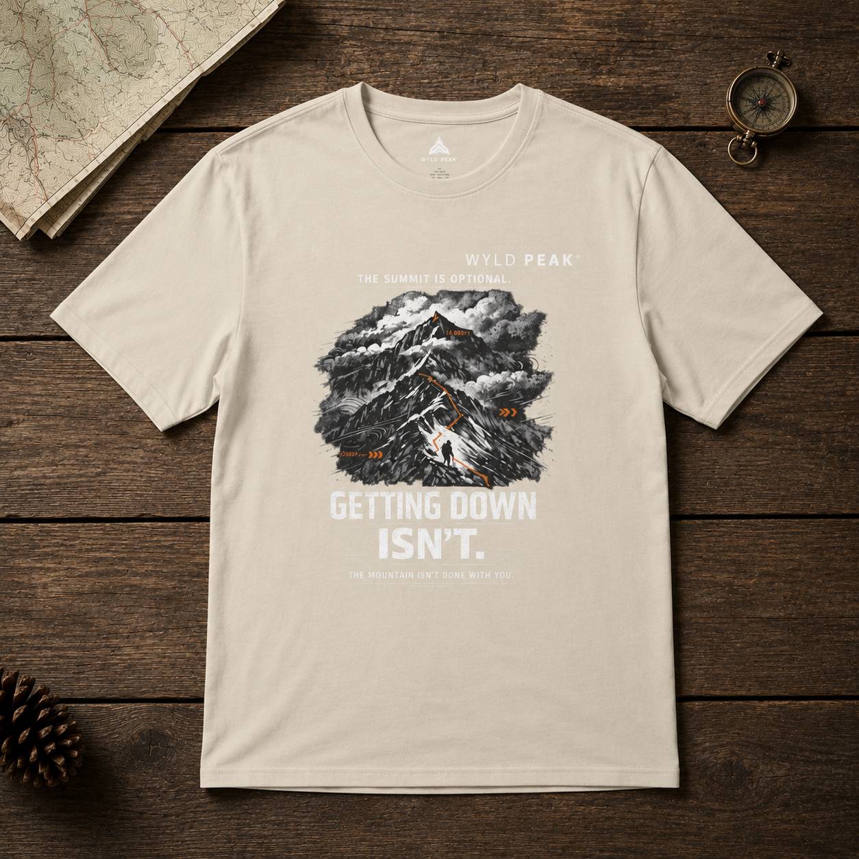 Beige t-shirt with mountain graphic and text on a wooden surface