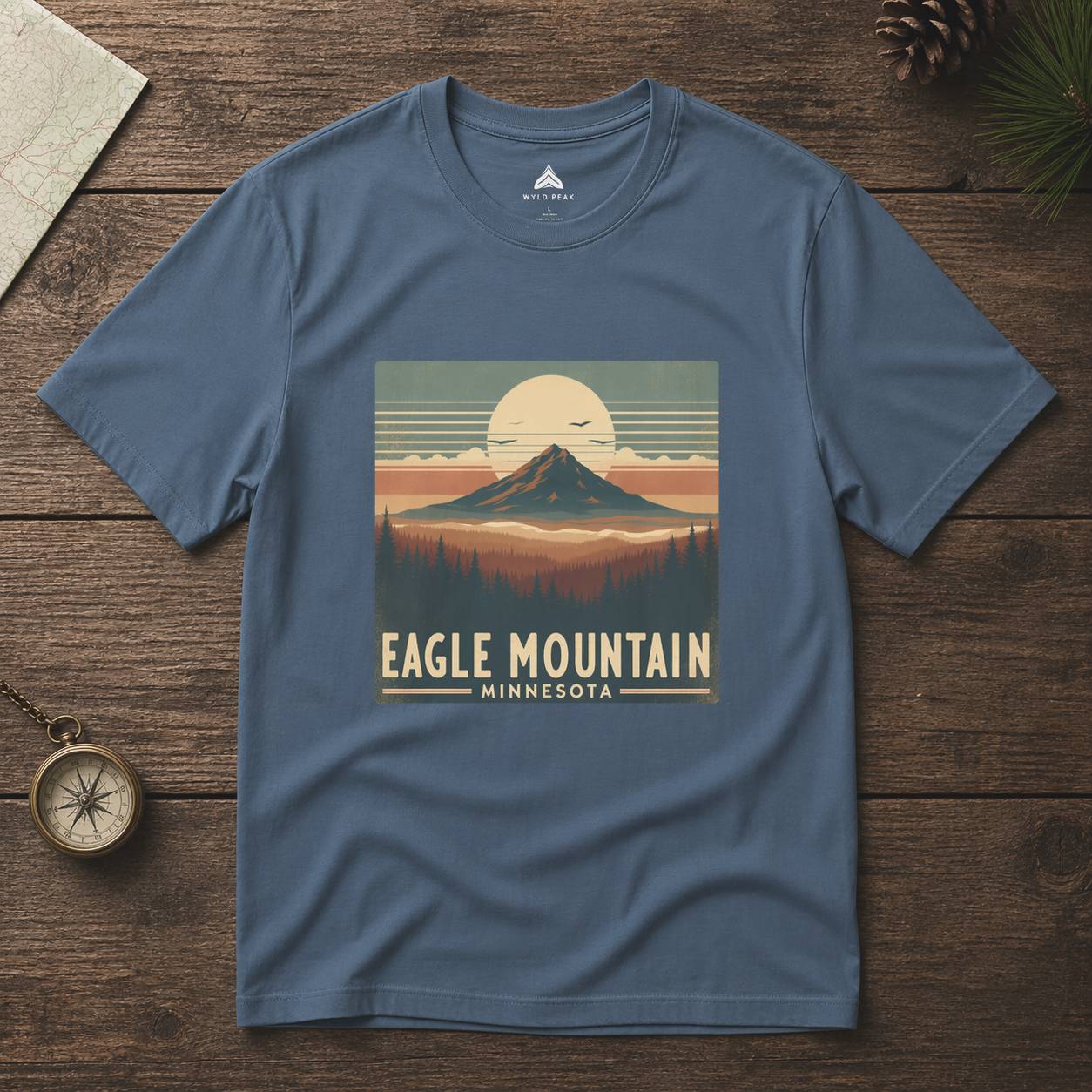 Blue t-shirt with 'Eagle Mountain, Minnesota' design on a wooden surface