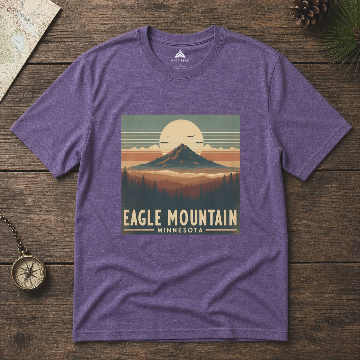 Purple t-shirt with 'Eagle Mountain, Minnesota' graphic on a wooden surface