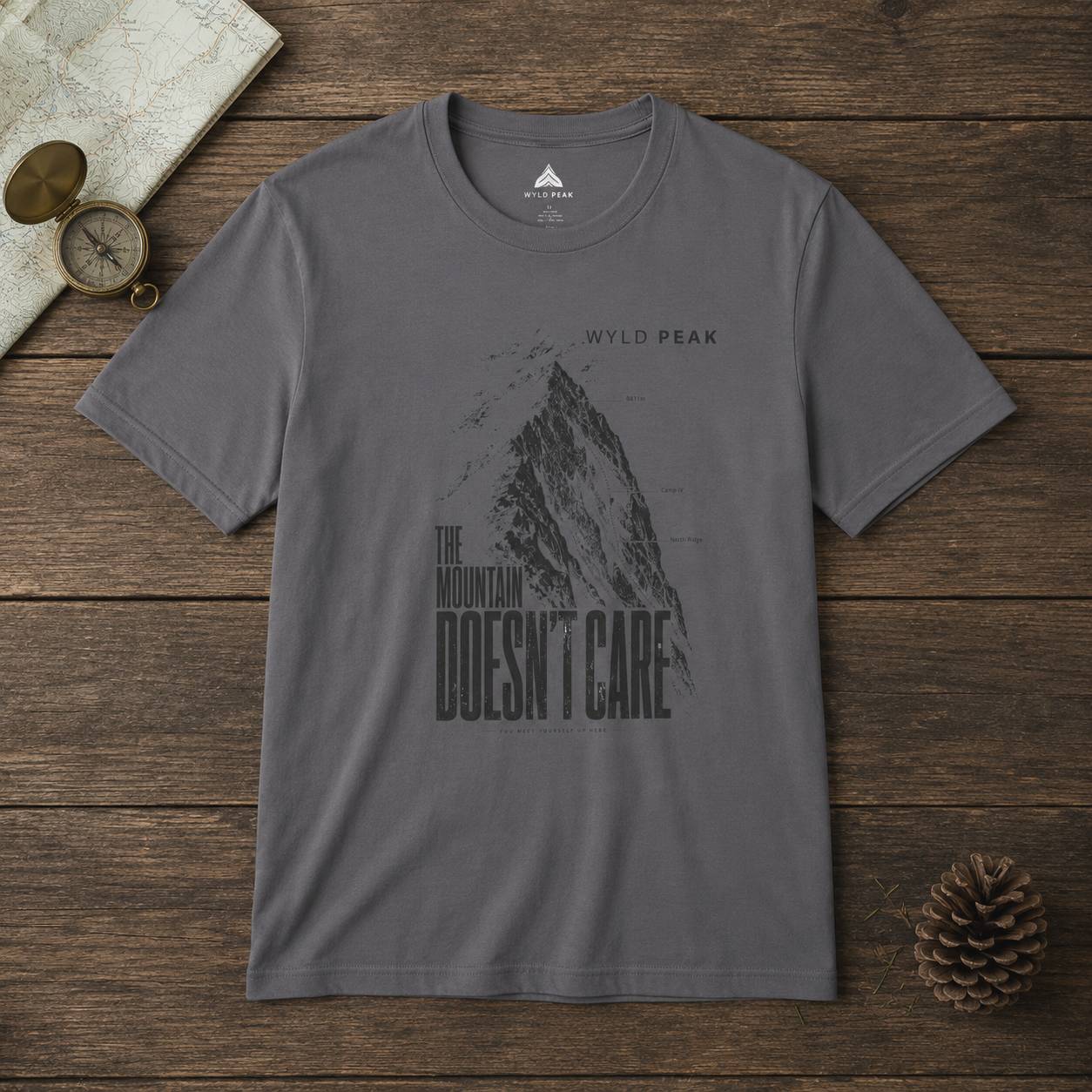 Gray t-shirt with mountain graphic and text on a wooden surface