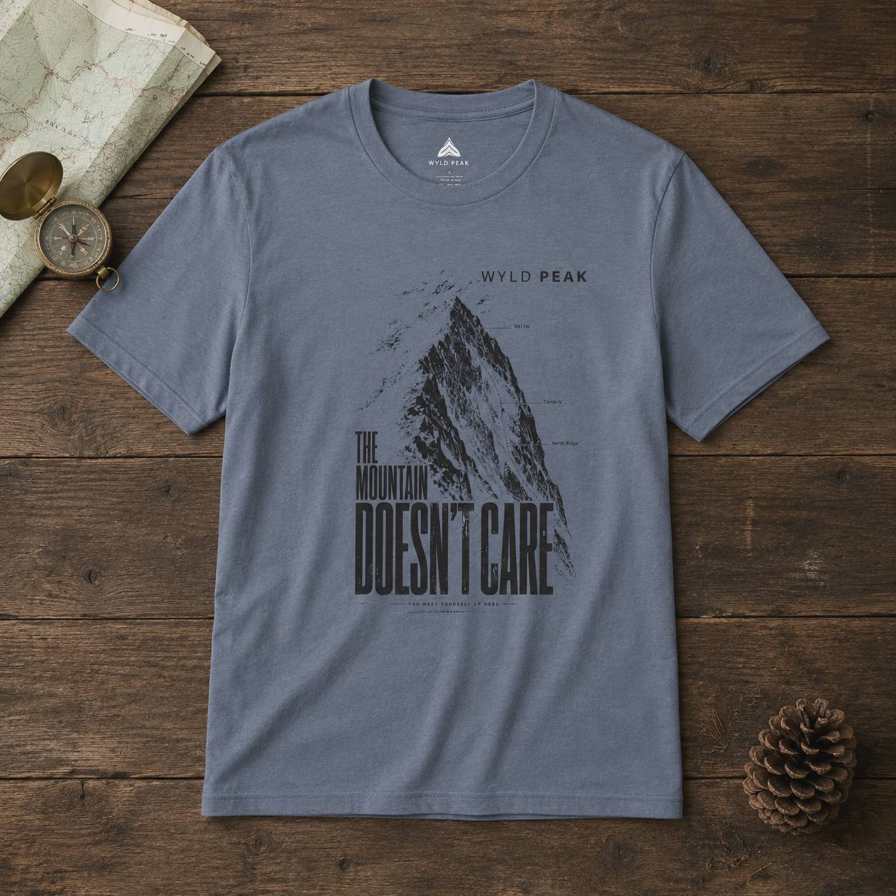 Gray t-shirt with mountain graphic and text on a wooden surface