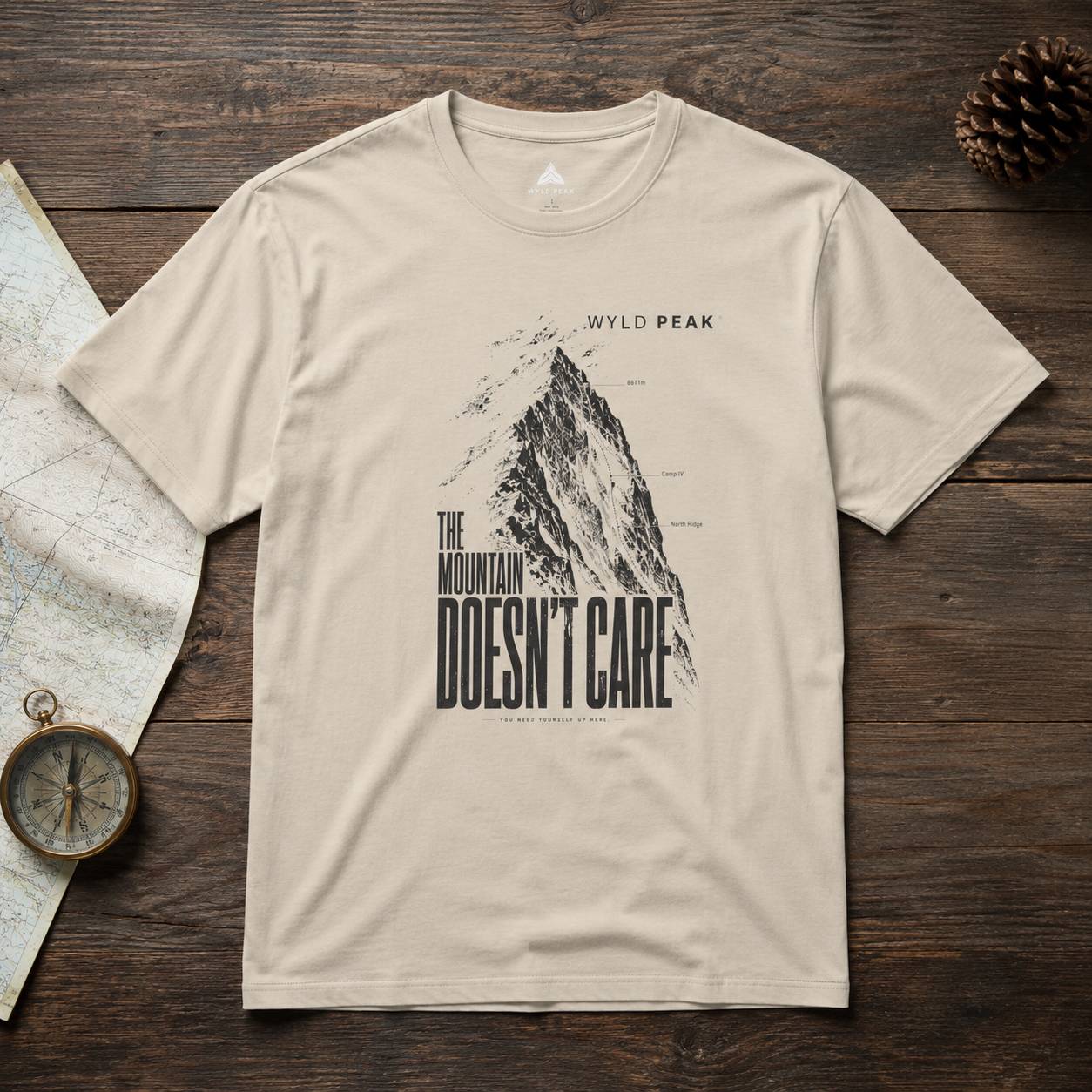 Beige t-shirt with mountain graphic and text on a wooden surface