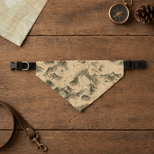 Map-patterned dog bandana on a wooden surface with a compass and pine cone.
