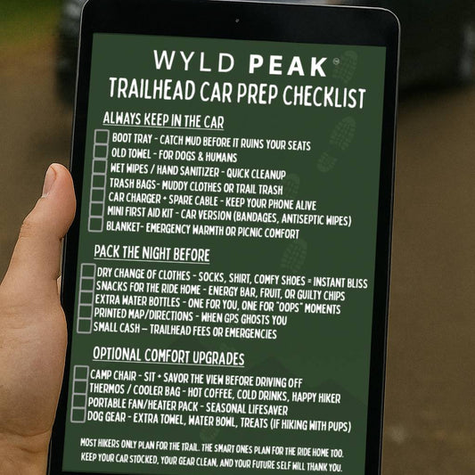 Tablet displaying Wyld Peak Trailhead Car Prep Checklist held by a hand with a car in the background.
