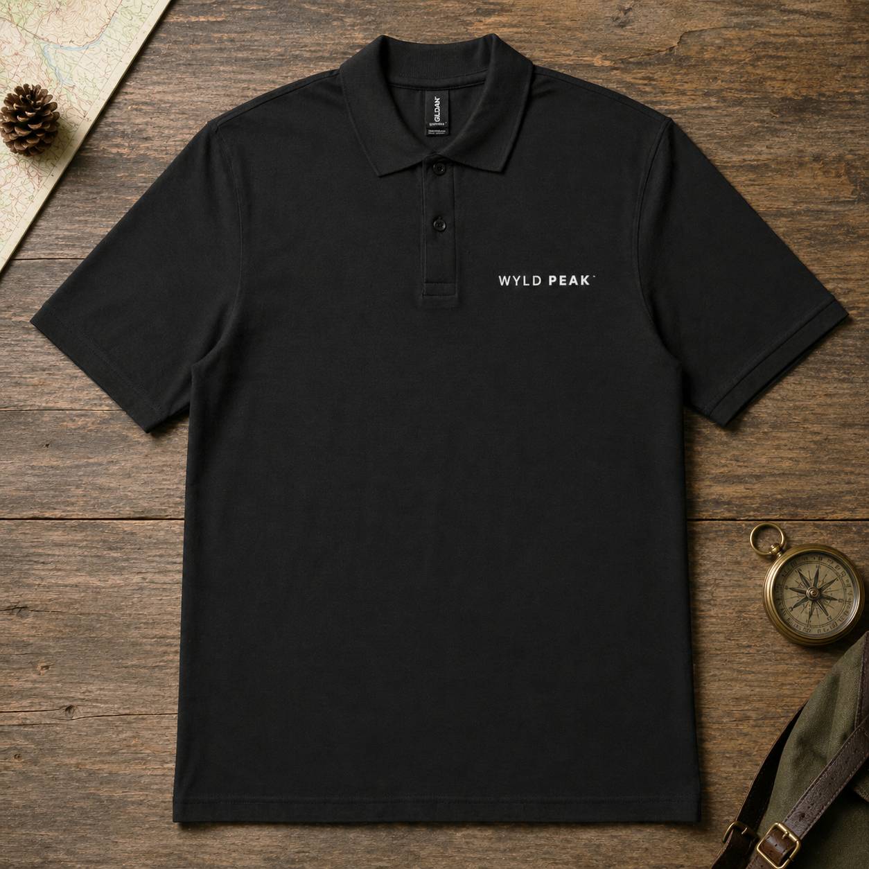 Black polo shirt with 'Wyld Peak' logo on a wooden surface