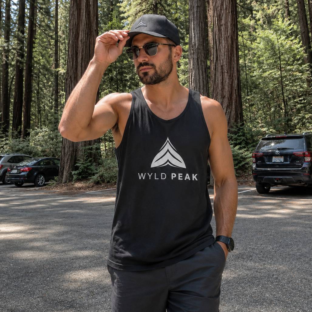 Man wearing a black tank top with 'Wyld Peak' logo in a forest setting
