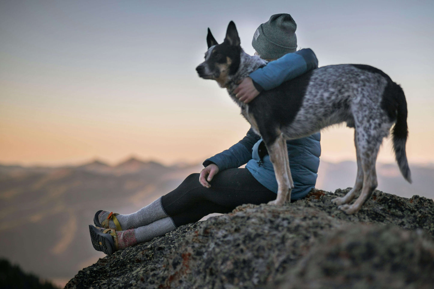 Woman celebrating a hike with her dog on a mountain summit.