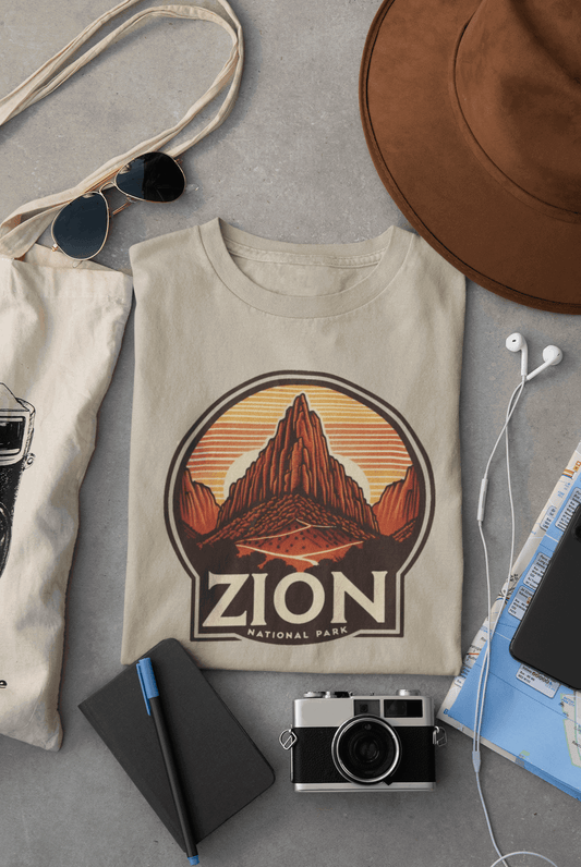 Wyld Peak Angels Landing Zion National Park organic cotton tee in desert tan laid flat on desk.
