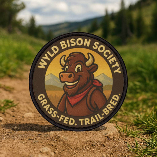 Bison Society patch held in a forest setting, heritage inspired outdoor design for rugged gear