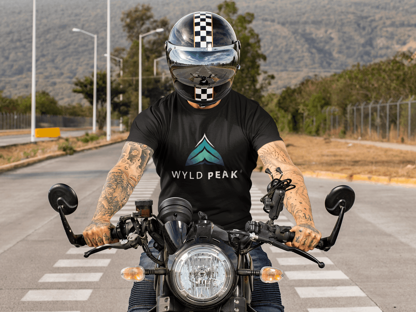 Man riding motorbike in California wearing black Wyld Peak branded men's organic cotton t-shirt